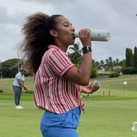 Woman golfing and drinking from Water.io bottle