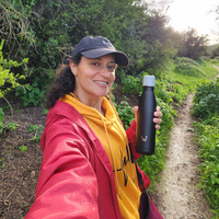 Woman smiling on a hike and holding Water.io bottle