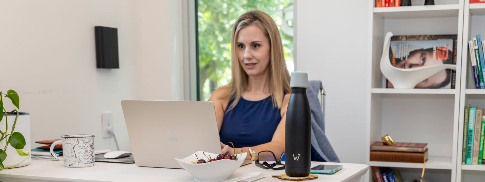 Woman working on laptop with Water.io bottle sitting on desk