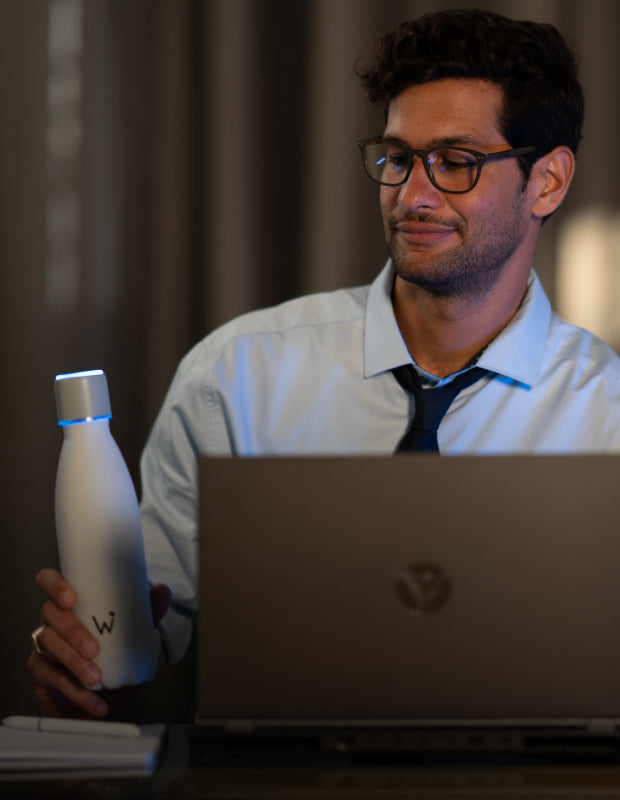 Man working on computer and holding Water.io bottle