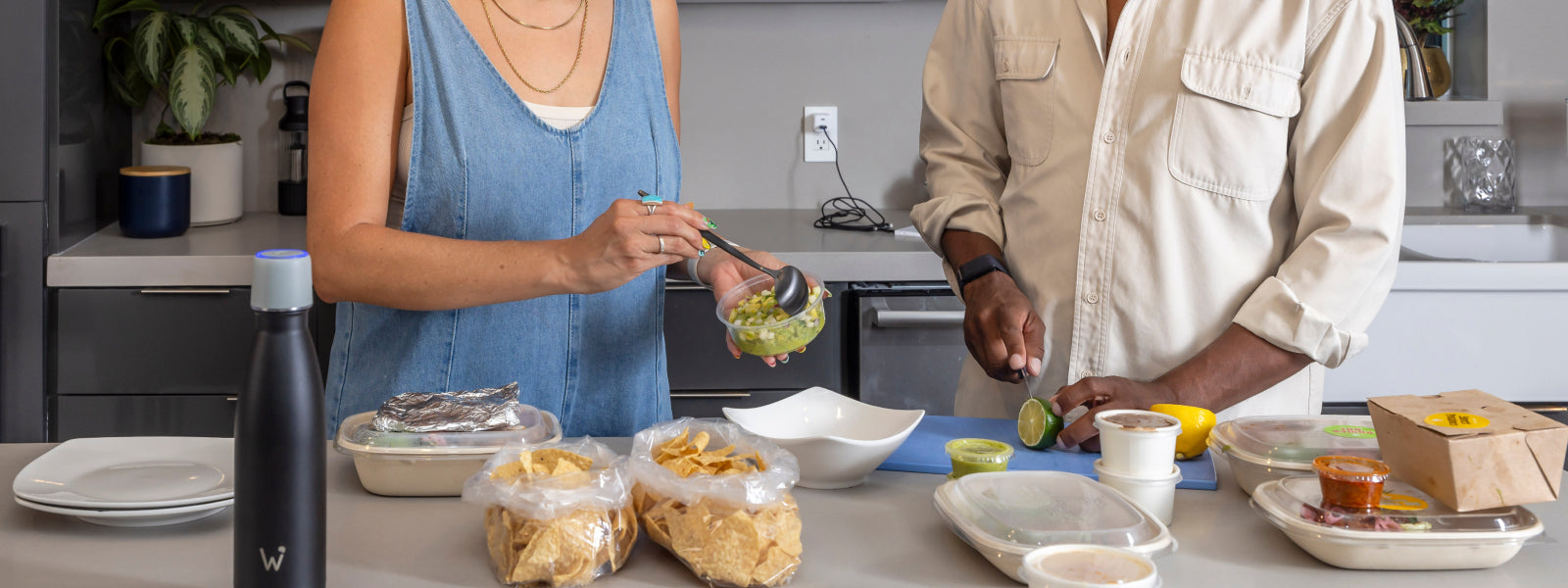 Woman and man preparing food in kitchen with Water.io sitting on counter.