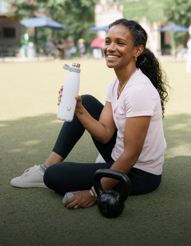 Woman sitting and smiling holding a Water.io bottle