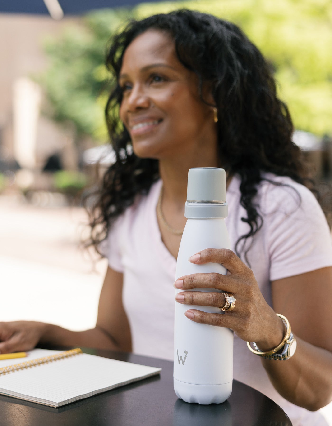 Woman writing in journal and holding Water.io bottle.